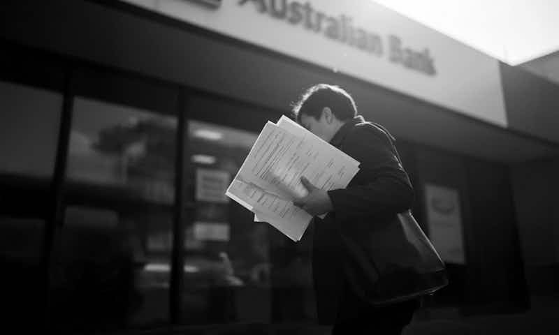 Person holding an envelope from the Australian Taxation Office, with computer monitors and paperwork in the background. Worrells.