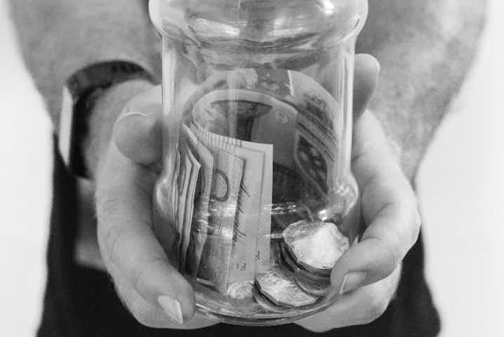 Photo of hands presenting cash in a jar.